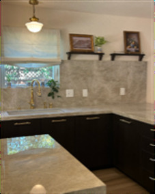 Kitchen sink with stone backsplash, brass faucet, and pendant light